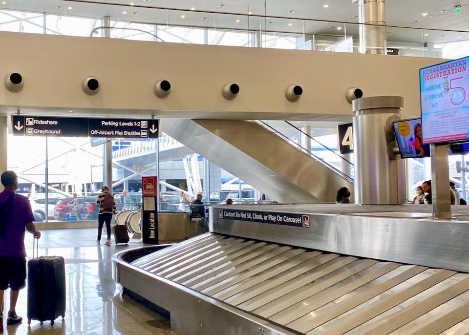 An escalator down to baggage claim leads to a sign directing people outside to Greyhound.