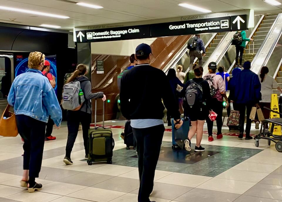 Passengers taking the escalators to the domestic baggage claim area.