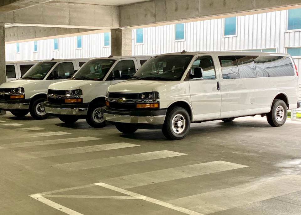 Full sized vans parked in the Budget section of the garage.