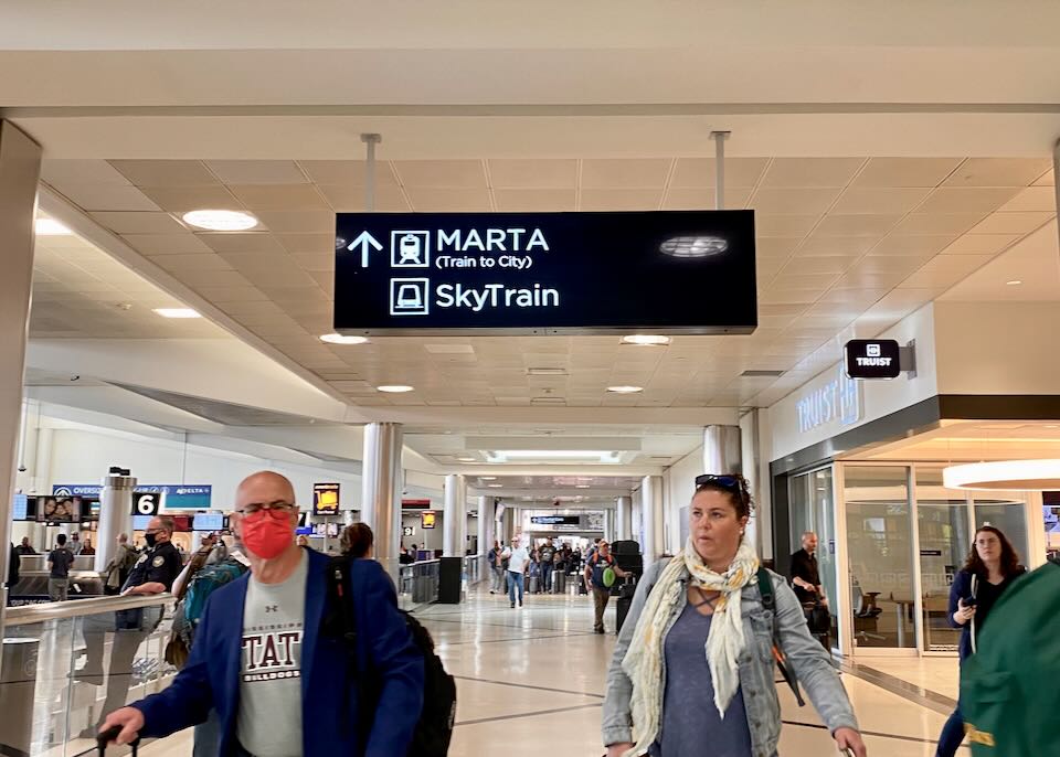 A sign inside the ariport with an arrow pointing north to "Marta, Train to City" and "Sky Train."