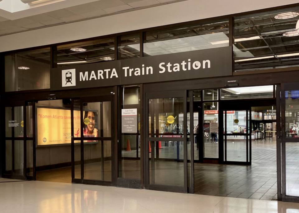 Inside the airport a sign sits for "Marta Train Station" sits above sliding glass doors.
