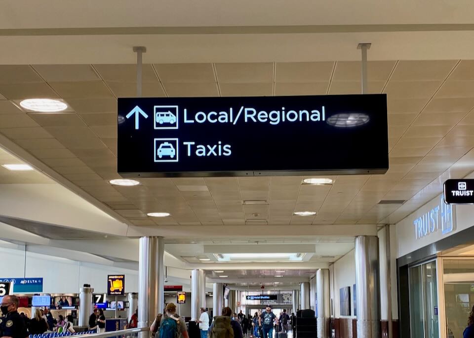 Inside the aiport a sign with an arrow pointing to the north states, "Local/Regional" and "Taxis" hangs from the ceiling.