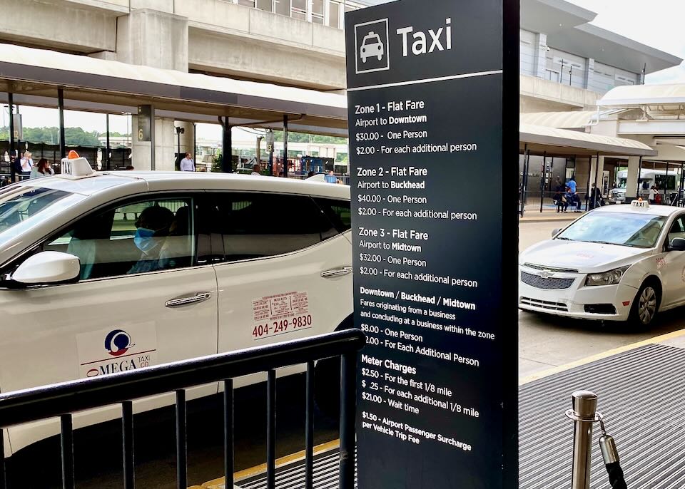 Outdoor taxi sign listing fares next to the taxi line up.