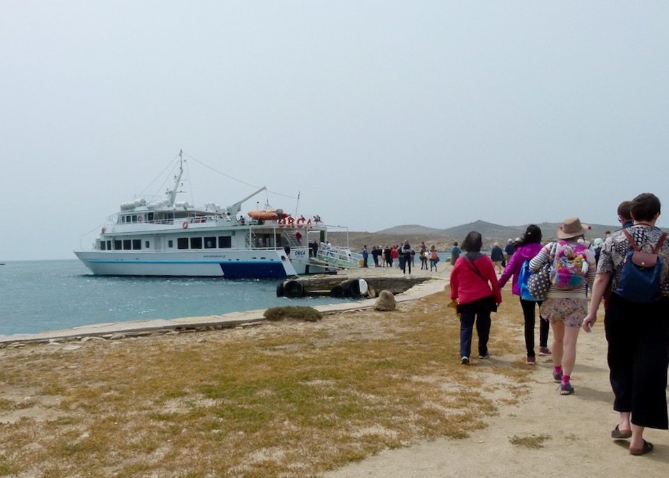 Dozens of tourists walk back to a tour boat docked on a rocky island