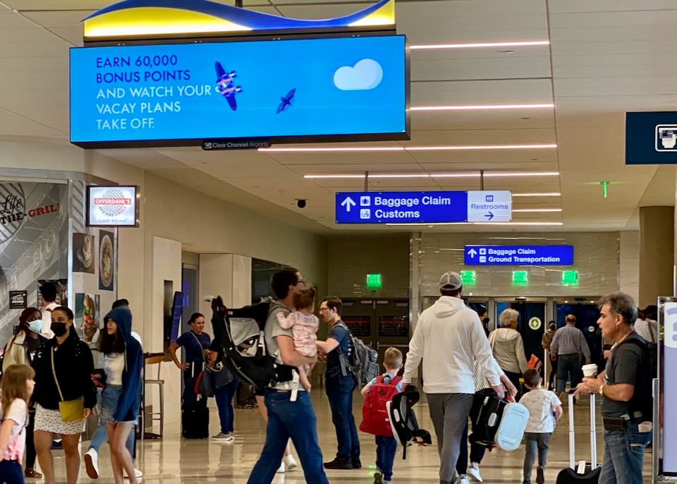 Inside Fort Lauderdale airport, blue signs point to Baggage Claim.