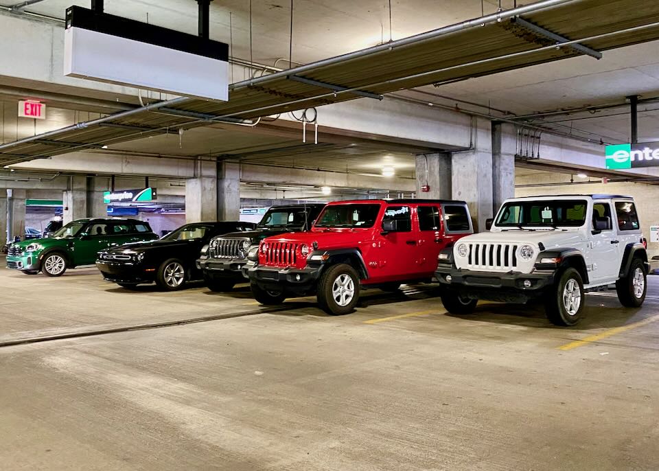 Two Jeeps, a Mini Cooper, and a Dodge Challenger sit in the garage.