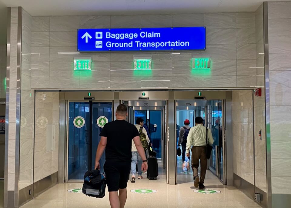 A man walks through exit doors to Baggage Claim.