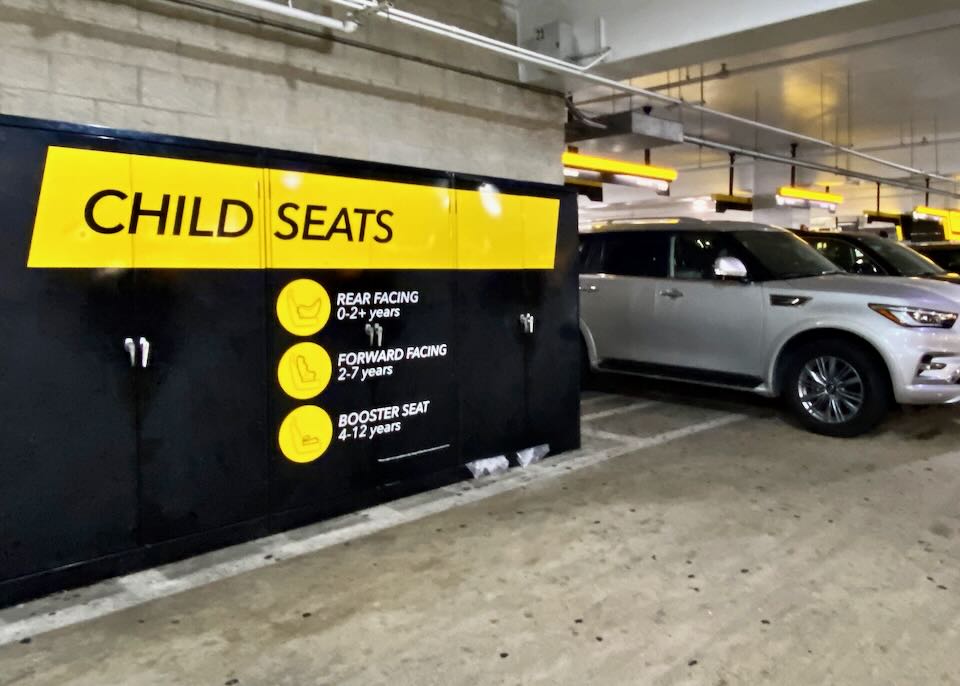 A yellow child seat sign on lockers in the Hertz area.