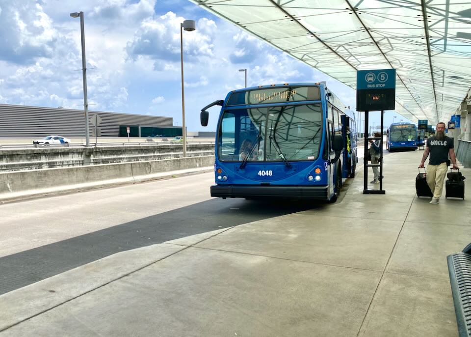 A blue bus pulls up to the bus stop number 5 stall.