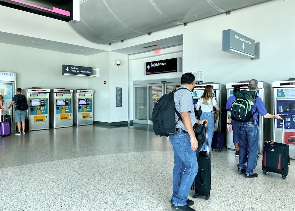 People stand in line to buy transportation tickets from a machine.