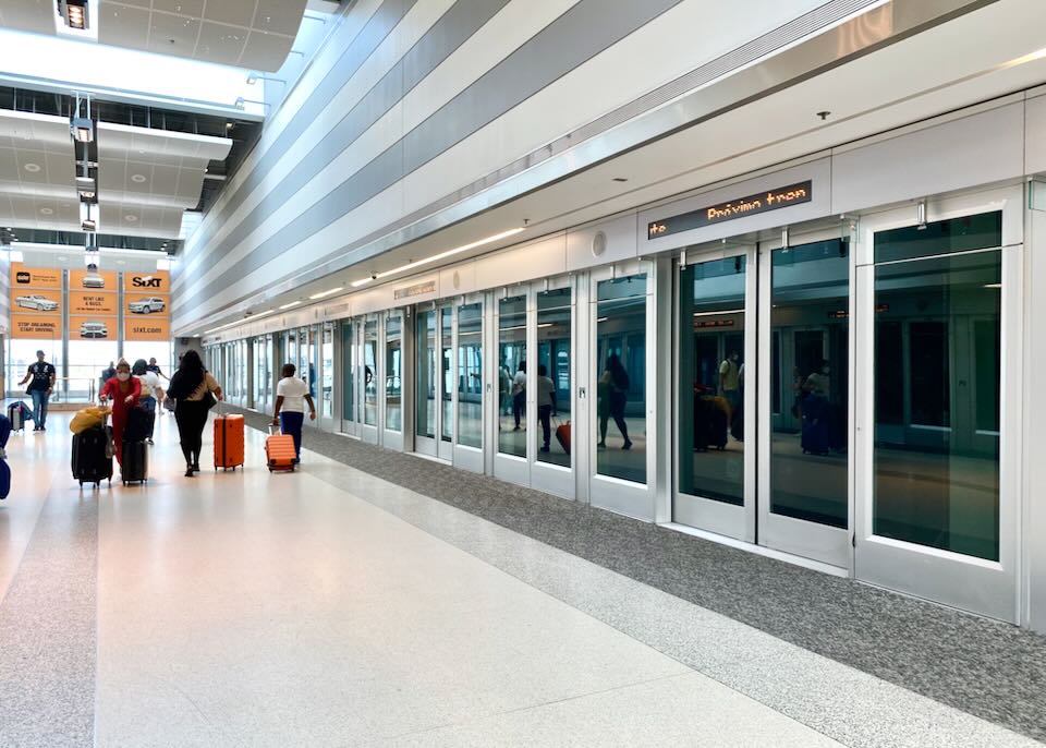 Passengers walk in front of the MIA Mover train doors.