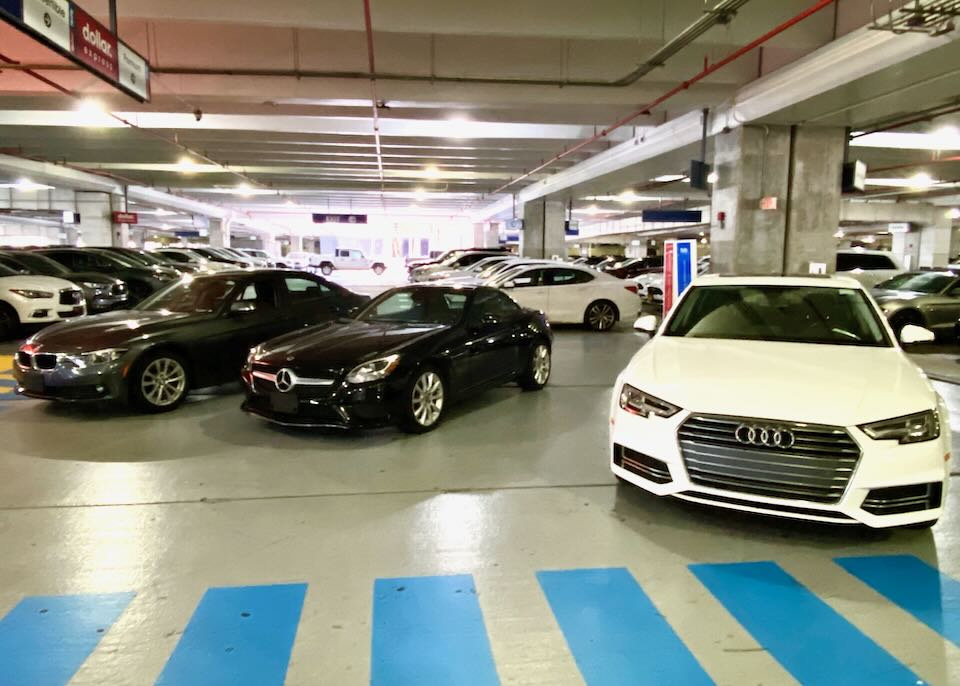 Three luxury cars are parked in the Dollar area of the garage.