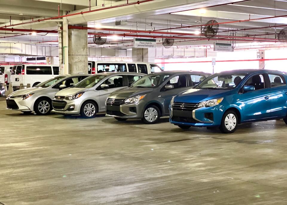 A row of cars are parked in the Enterprise section of the garage.