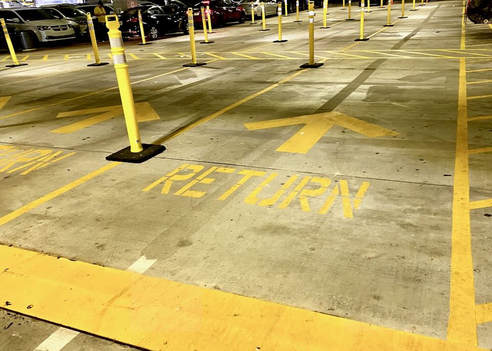Painted yellow signs on the garage floor read, Return with an arrow pointing north.