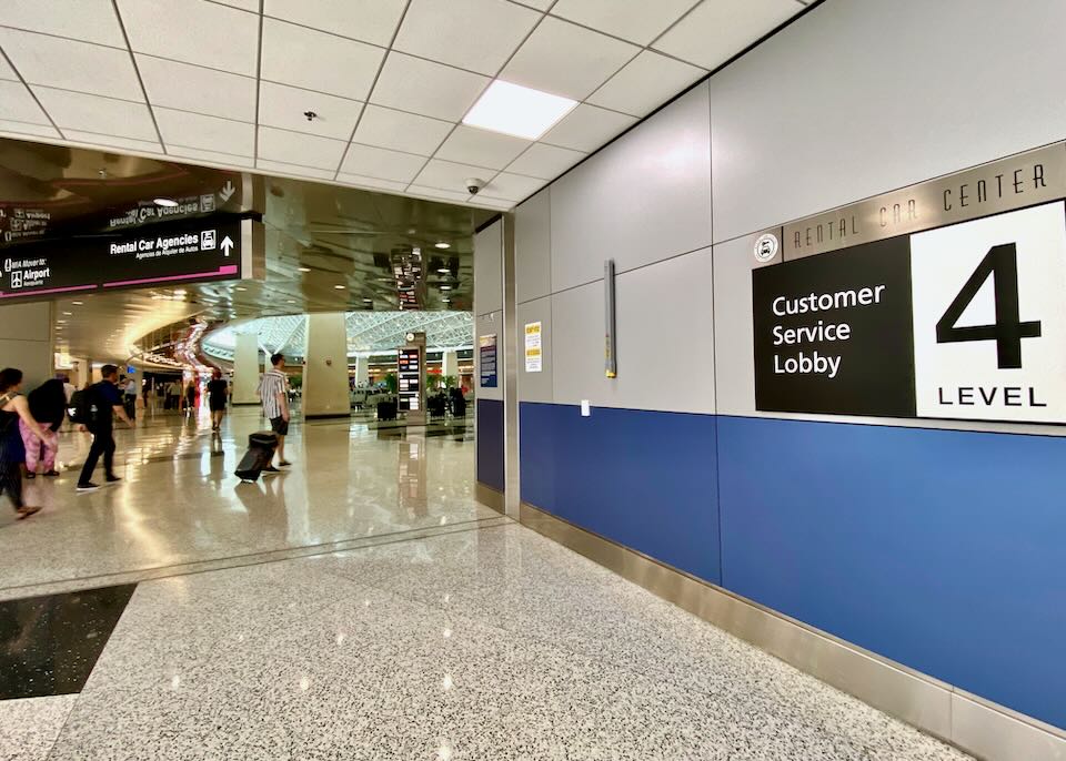 Inside the airport Rental Car Center, a sign on the wall reads Customer Service Lobby, Level 4.