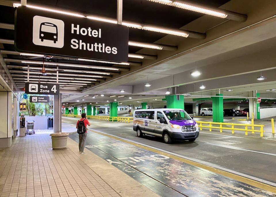 A shuttle drives by the Hotel Shuttles area outside the airport.
