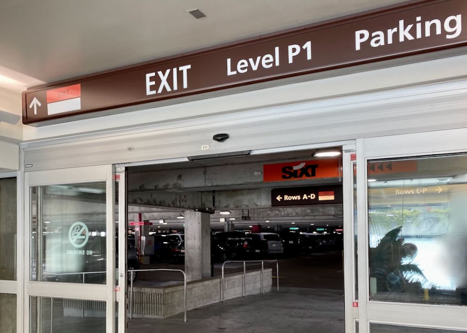 An overhead exit sign reads, Level P1 Parking and an arrow to Sixt.