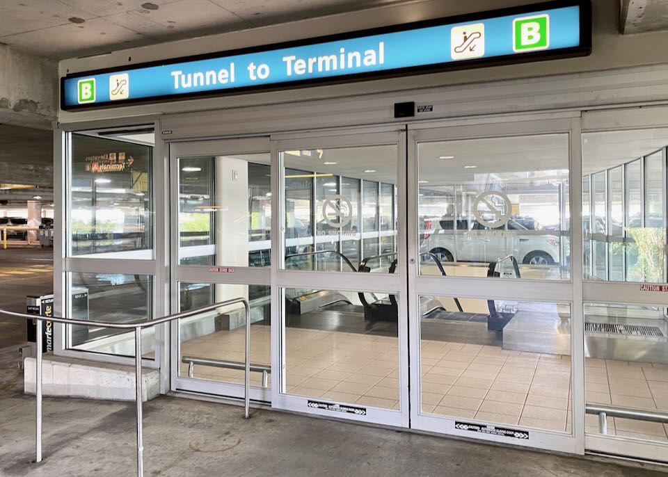A sign above the doors directs people to an escalator down to the tunnel to the main terminal.
