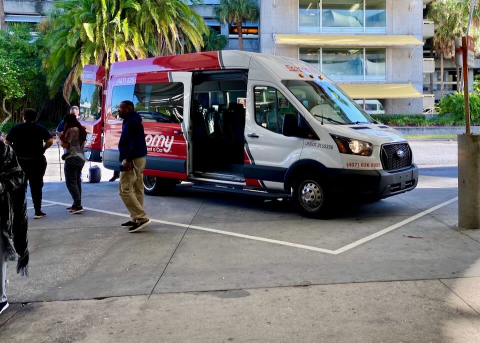 A red off-stie shuttle van picks up passengers.