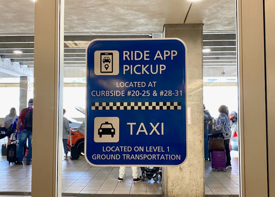 A sign on the door reads, ride app pickup located at curbside #20-25 & #28-31. Taxi located on level 1 ground transportation.