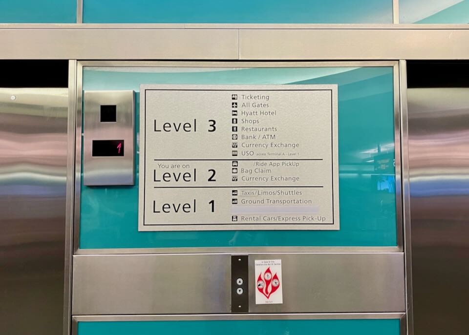 A sign between two elevators shows what is on Level 1-3.
