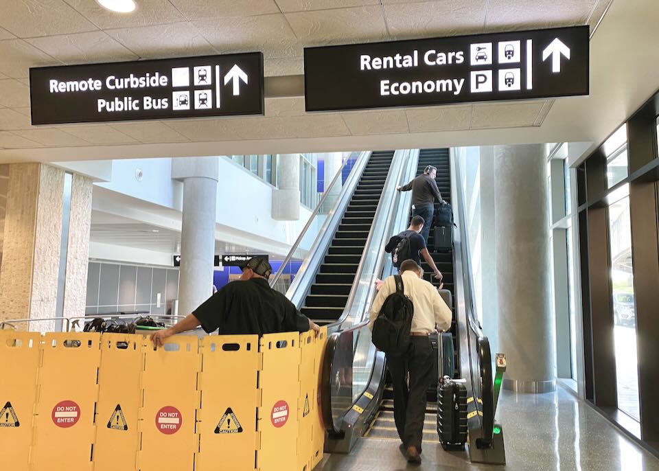 People ride the escalator up to Rental Cars.