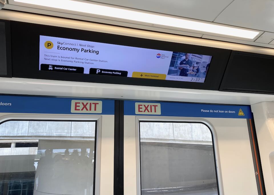 Onboard the train, an electric sign shows the next stop is Economy Parking.