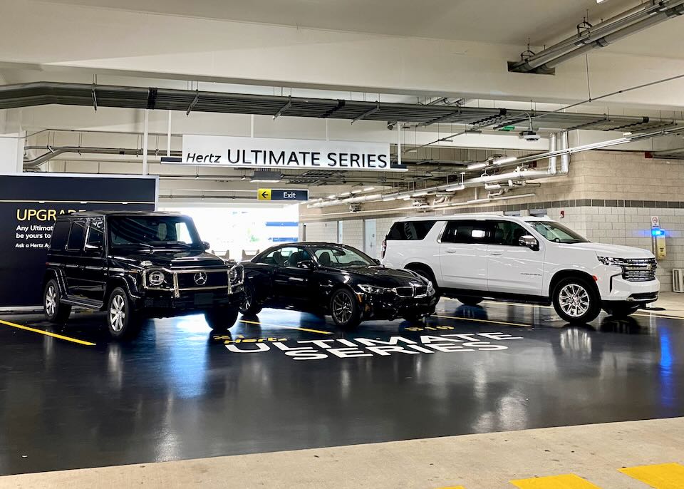 Luxury vehicles sit in the Hertz Ultimate Series section of the garage.