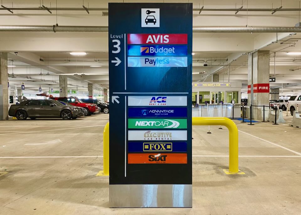 A sign in the parking garage directs people to their rental car agency.