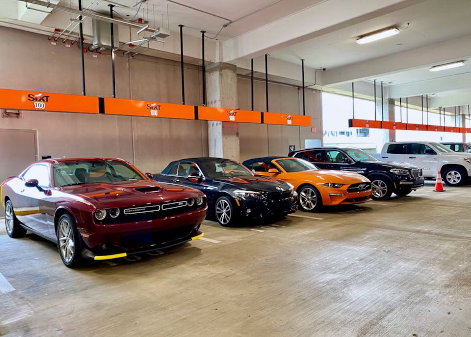 Luxury sports cars sit in the Sixt section of the garage.