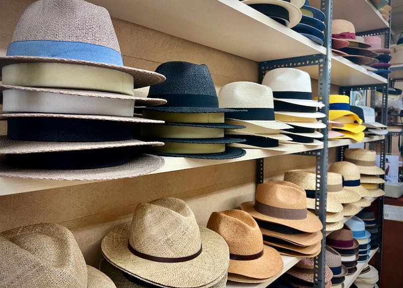 Straw fedoras with colorful bands stacked on a shelf