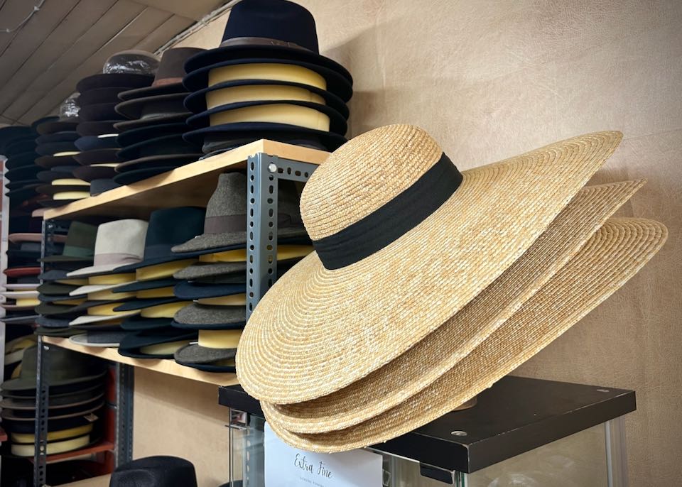A wide-brimmed straw hat, hanging on a shop wall