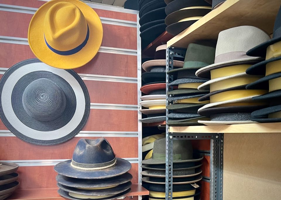Stacks of felt fedoras, with a few hanging on a wall