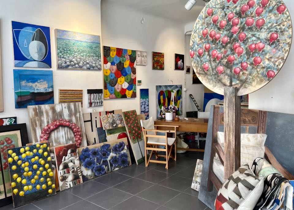 An art studio and gallery space with colorful paintings displayed on the wall and floors
