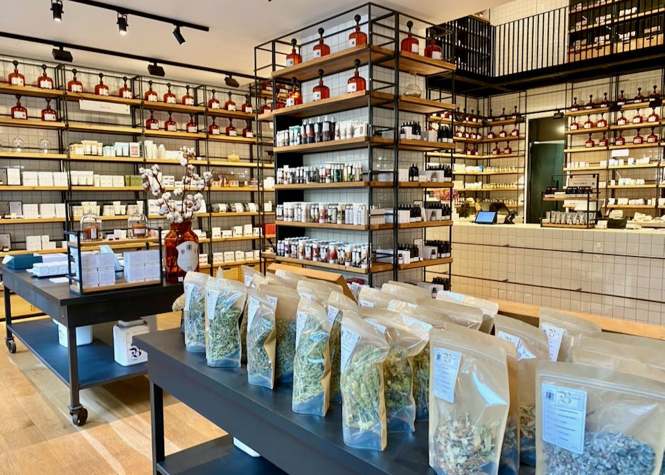 Store with shelves lined with cosmetic items, and a table displaying bags of herbs
