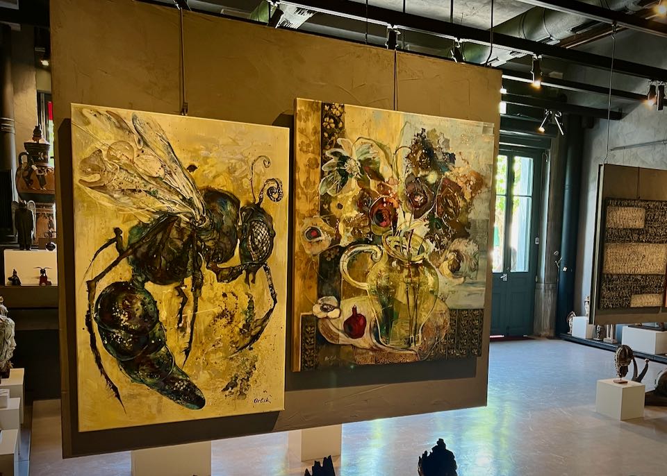 Abstract paintings of a bee and flowers hung in a gallery