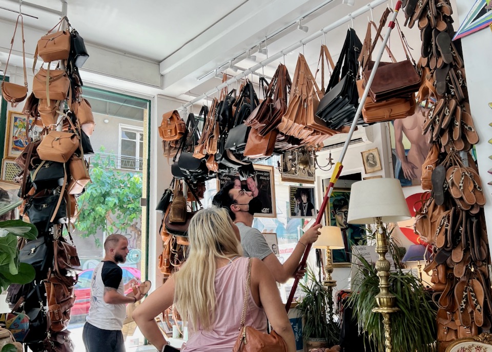 A man helps a woman reach a leather purse hung from the ceiling