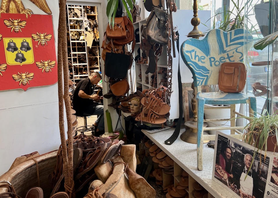 A crowded shop hung with leather sandals and purses, with a sandalmaker working in the back