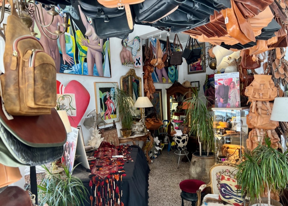 Crowded and colorful sandal shop, hung with leather goods and vibrant artwork