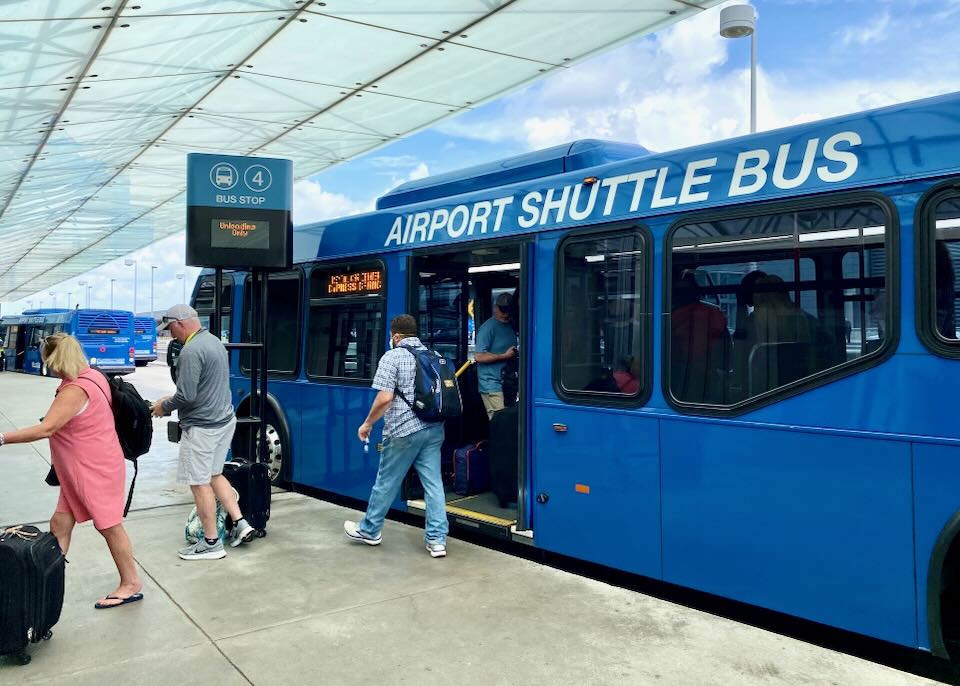 People exit a blue Airport Shuttle Bus.