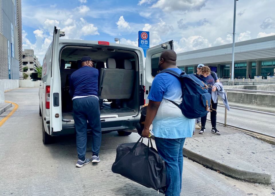 People load their luggage into an off-airport shuttle van.