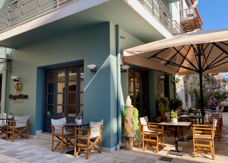 Exterior of a boutique hotel with cafe tables in front