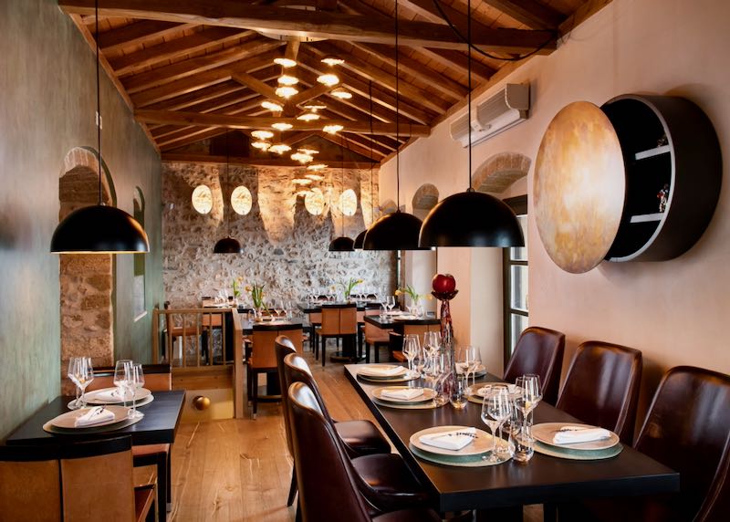 Intimate dining room with stone walls and timber ceiling, set for fine dining service