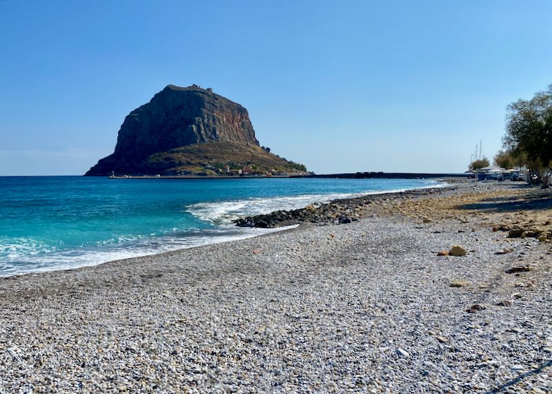 Pebbly beach with crystal blue water and a view to Monemvasia rock