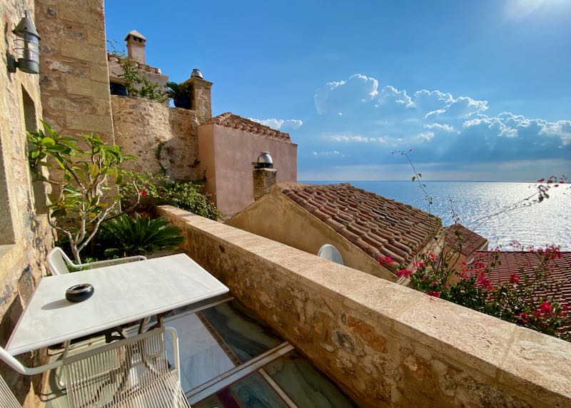 View from a balcony over romantic stone buildings to the blue sea