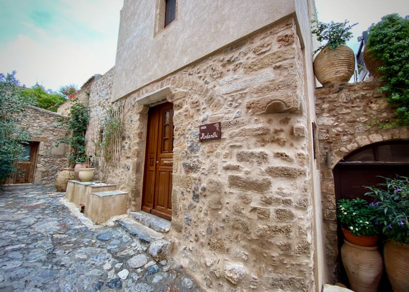 Rustic stone building with wooden doorways and potted plants in front