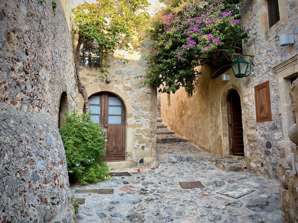 Stone pathway with wooden doorways and bouganvilla overhead