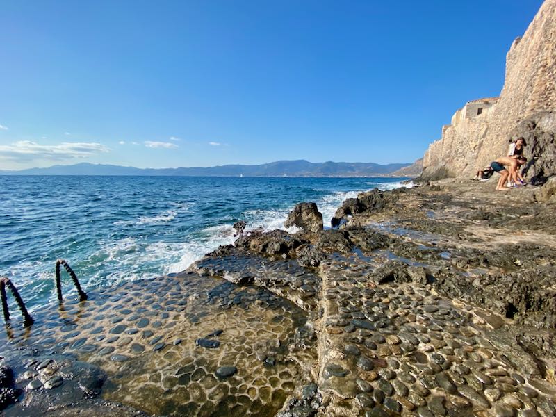 Rocky outcrop from a stone sea wall, with a ladder leading down into the water