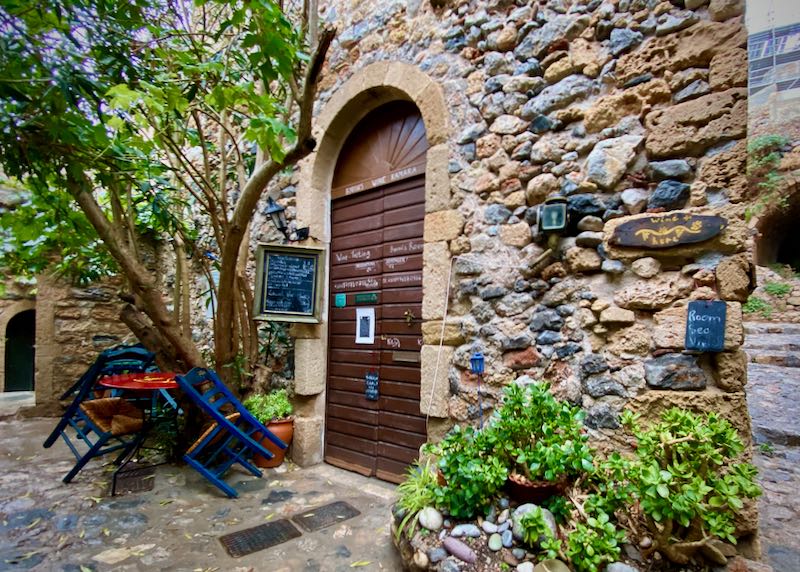 Exterior of a small wine bar in a stone building with a heavy wooden doorway