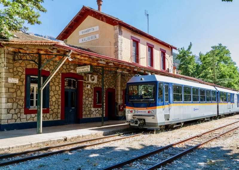 Train at a rustic mountain train station labeled "Kalavryta" in Greek
